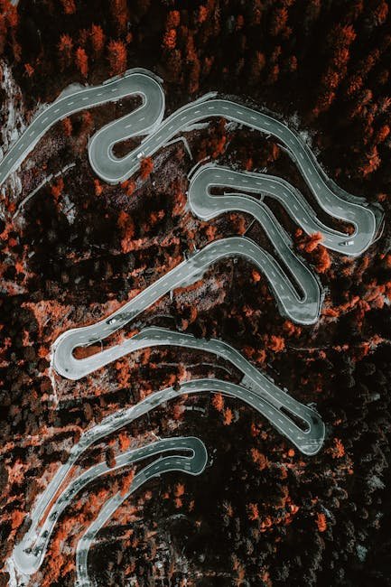 Aerial shot of winding road through autumn forest in Maloja, Switzerland.